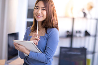 Portrait of a smiling young woman using mobile phone