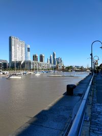 River by buildings against clear blue sky