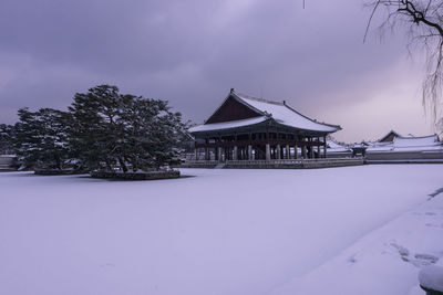 House on snow covered field against sky