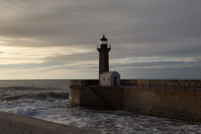 Lighthouse by sea against sky