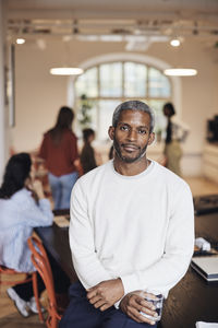 Portrait of male business professional sitting at desk in coworking office