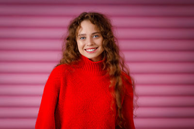 Portrait of young woman standing against wall