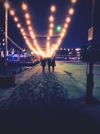 Rear view of people in illuminated city at night during winter