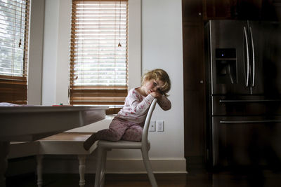 Portrait of bored girl sitting on chair at home