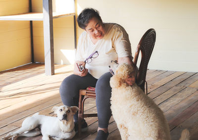 Woman sitting on chair with dogs on floor