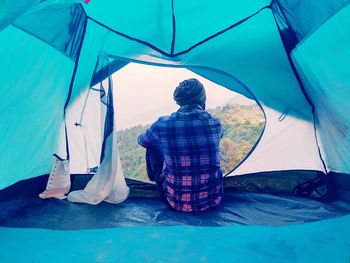 Rear view of man sitting at tent