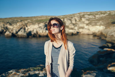 Young woman wearing sunglasses standing on rock