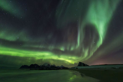 Scenic view of beach against aurora borealis at night