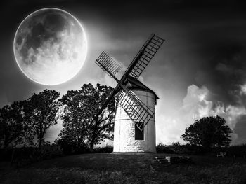 Low angle view of windmill and trees against sky