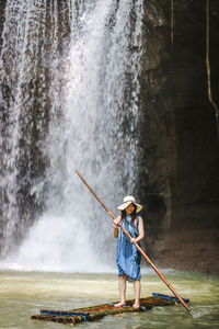 Full length of woman standing against waterfall