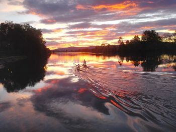 Reflection of trees in water at sunset