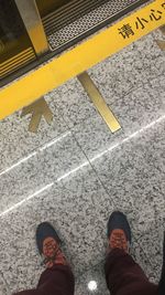 Low section of man standing on tiled floor