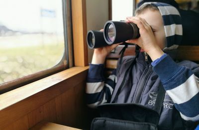 Boy using binoculars in train