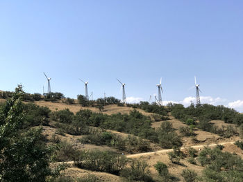 Wind turbines on field against clear sky