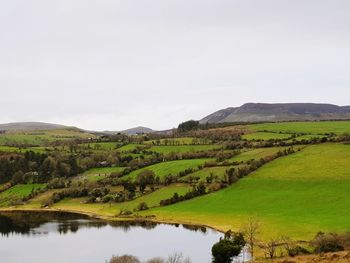 Scenic view of lake amidst field against sky