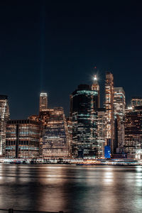 Illuminated modern buildings in city against sky at night