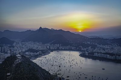 Scenic view of buildings and mountains against sky during sunset