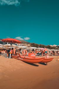 Boats moored on beach against blue sky