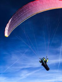 Woman paragliding against blue sky