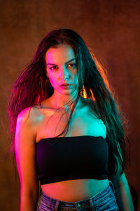 Portrait of young woman standing against wall