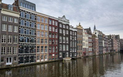 Buildings by canal against sky
