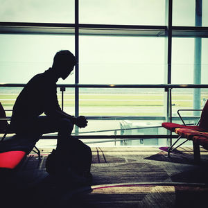 Side view of silhouette man sitting at airport