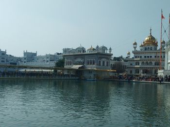 View of buildings by river against clear sky