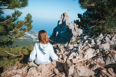 Rear view of woman sitting on rock