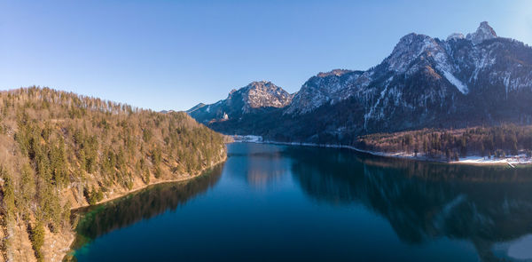 Scenic view of lake alpsee and mountains against clear blue sky