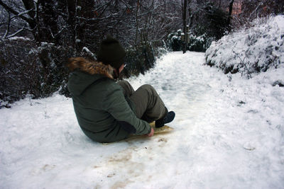 Man sitting on snow covered land