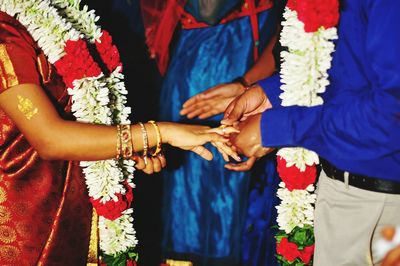 Midsection of groom putting wedding ring in bride finger