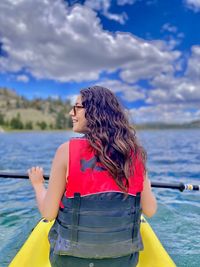 Woman standing by boat in sea against sky