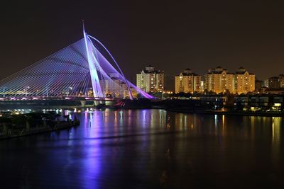 Illuminated bridge over river with city in background