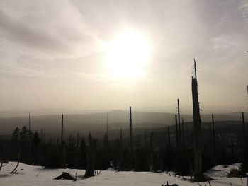 Snow covered landscape against sky during sunset