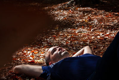 Man lying down on leaves during autumn