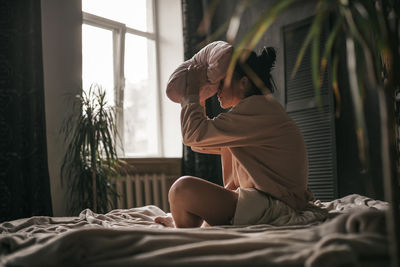 Woman sitting on bed at home