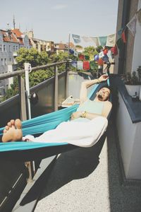 Man lying in hammock on balcony