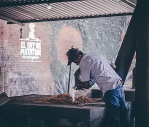 Side view of man working on wall