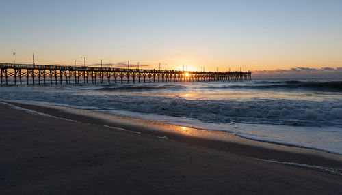 Scenic view of beach against clear sky during sunset