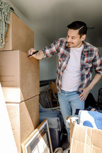 Man writing on cardboard box while standing in truck