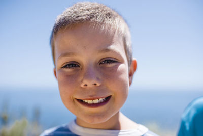 Portrait of smiling boy against sea and sky during sunny day