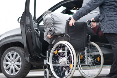 A woman helps aphysical disabled person to get into the car.