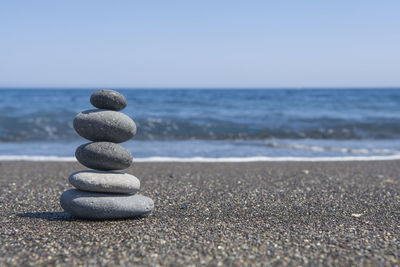 Stack of stones on beach against sky