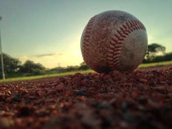 Surface level of ball on field against sky during sunset