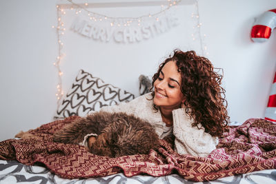 Beautiful young woman lying down at home with her dog at chritsmas