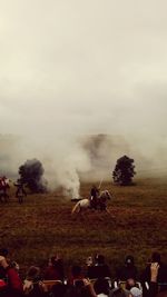 People riding horse on field against sky