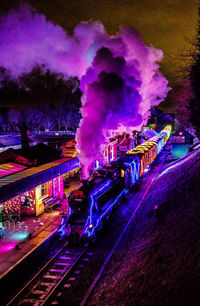 Illuminated railroad tracks by street at night