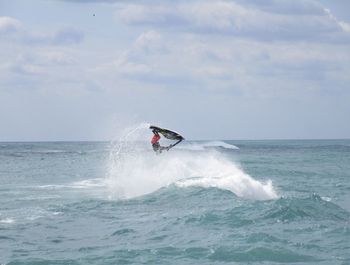 Man jet boating on sea against cloudy sky