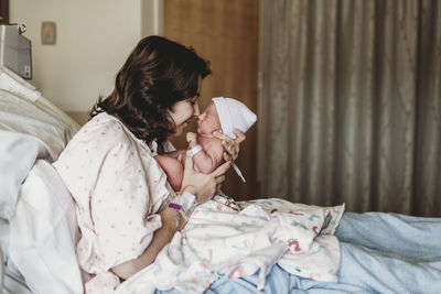 Side view of mother and newborn son touching noses in hospital