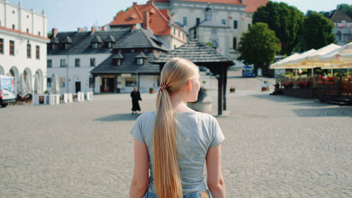 Rear view of woman standing on street in city